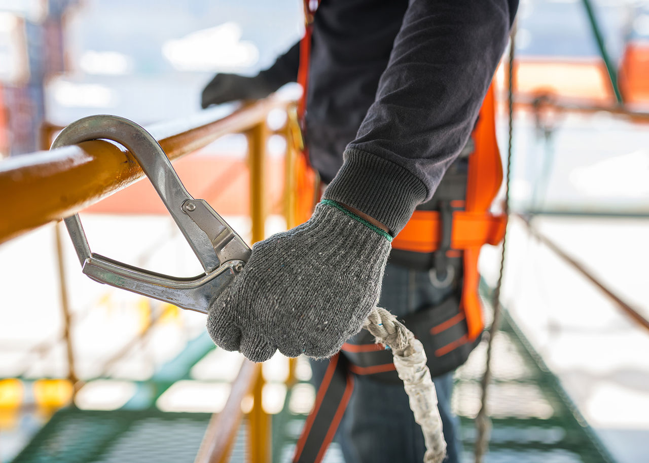 Person on scaffolding with safety rope clamped to a railing