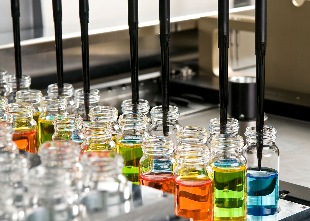 Vials being filled with colorful liquid by a machine