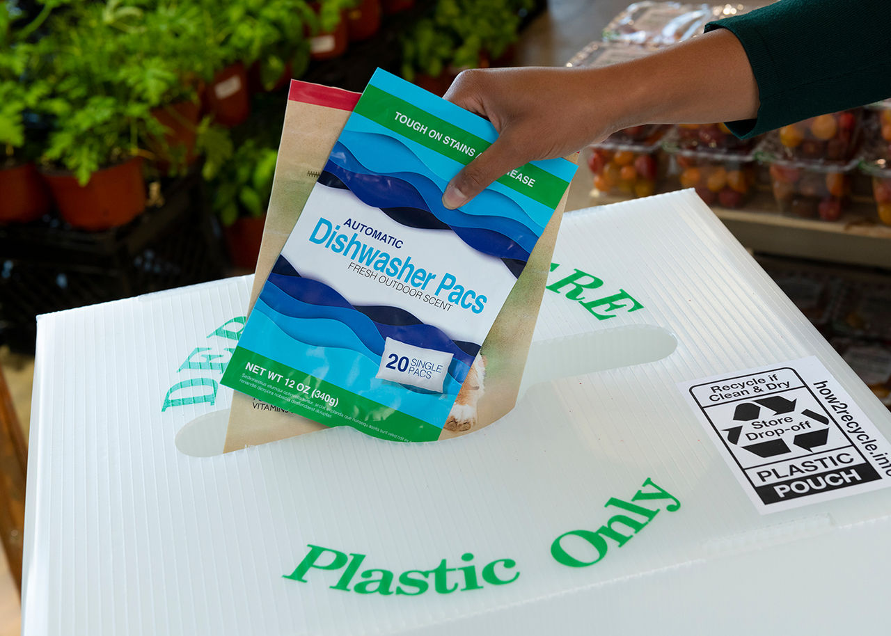 Recyclable plastic pouches being placed into an in store recycling container